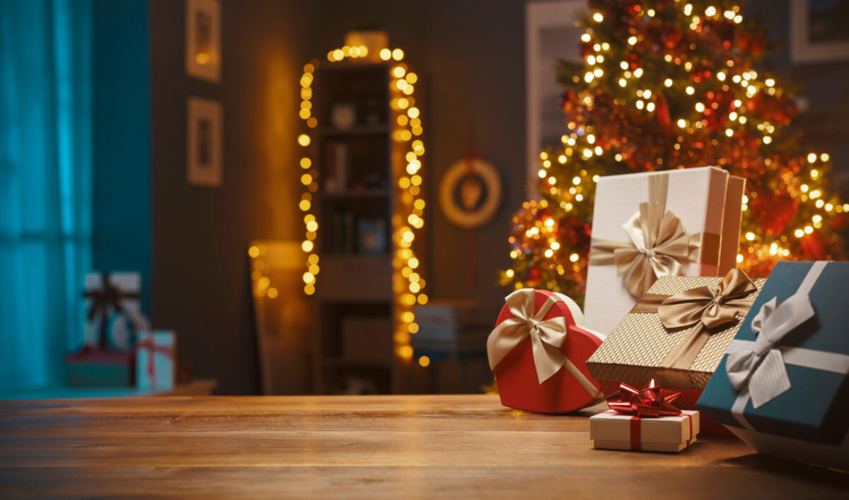 Natale: niente regali per un italiano su sei - Beautiful Christmas gifts on a table at home and tree with lights in the background, festivity and holiday concept