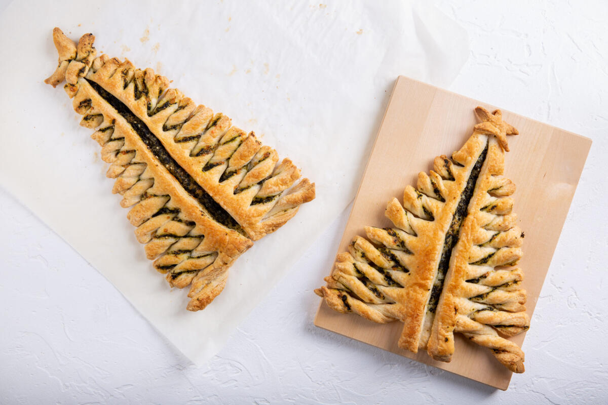 Come utilizzare la pasta sfoglia a Natale - Puff pastry pie with cheese and spinach in shape of  Christmas tree  on white background. Top view. Copy space.