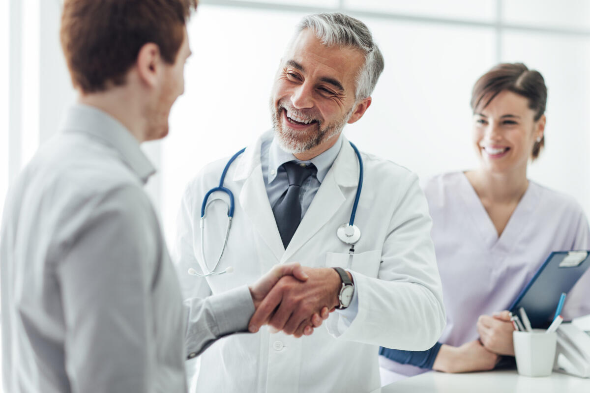 Sanità, pensionamenti e mancate sostituzioni, migliaia pazienti senza medico di base - Smiling doctor at the clinic giving an handshake to his patient, healthcare and professionalism concept